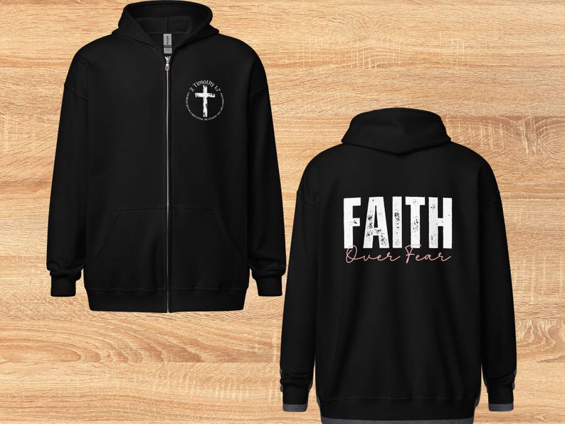 Puede incluir: Sudadera con capucha negra con cremallera, con una cruz blanca y el texto "2 Timoteo 1:7" en la parte delantera y el texto "FAITH Over Fear" en la parte trasera.