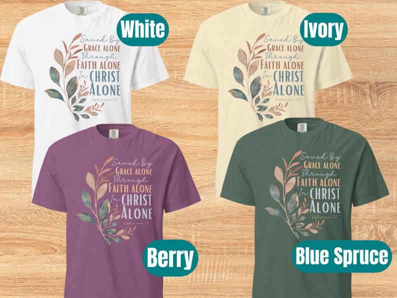 May include: Four t-shirts in different colours with a floral design and the text "Saved By Grace Alone Through Faith Alone In Christ Alone Ephesians 2:8". The colours are white, ivory, berry, and blue spruce.