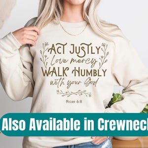 May include: A cream-colored sweatshirt with a brown graphic that reads "Act justly, love mercy, walk humbly with your God, Micah 6:8". The graphic is surrounded by small floral designs.