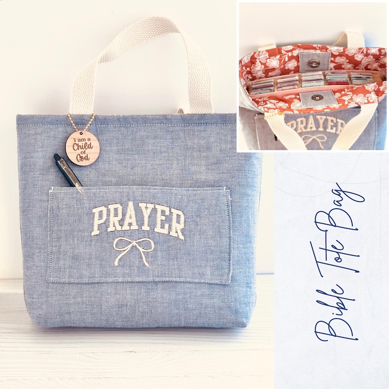 May include: A blue denim tote bag with a white handle and a front pocket. The pocket has the word "PRAYER" embroidered in white, with a bow below. A wooden tag with the text "I am a Child of God" hangs from the handle.