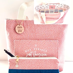 Puede incluir: Bolso tote rosa y estuche a juego con lunares blancos. El bolso tiene un asa blanca y un bolsillo frontal con el texto "Not Perfect Just Forgiven". El estuche tiene una base azul y una cremallera dorada. Un dije de madera dice "Faith Over Fear".