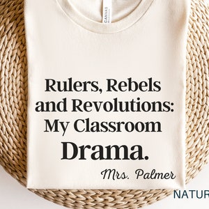 Peut inclure: Un t-shirt blanc avec le texte "Rulers, Rebels and Revolutions: My Classroom Drama. Mrs. Palmer" imprim&eacute; en noir.