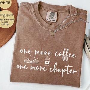 May include: A brown t-shirt with the text "one more coffee one more chapter" in white. The shirt also features a white illustration of a book with stars and a coffee cup.