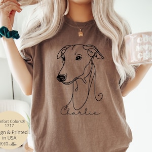 May include: Espresso-colored t-shirt featuring a line drawing of a dog's head with the name "Charlie" below. The shirt is made of 100% cotton and is printed in the USA. The shirt has the Comfort Colors 1717 label.