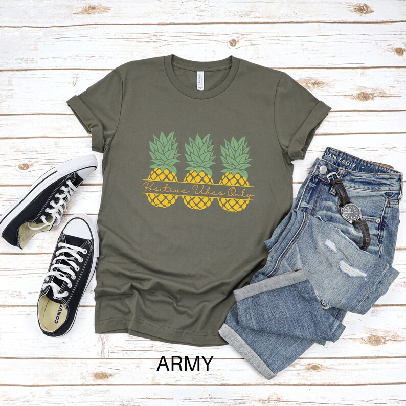 May include: Army green t-shirt with a graphic of three pineapples and the text "Positive Vibes Only".