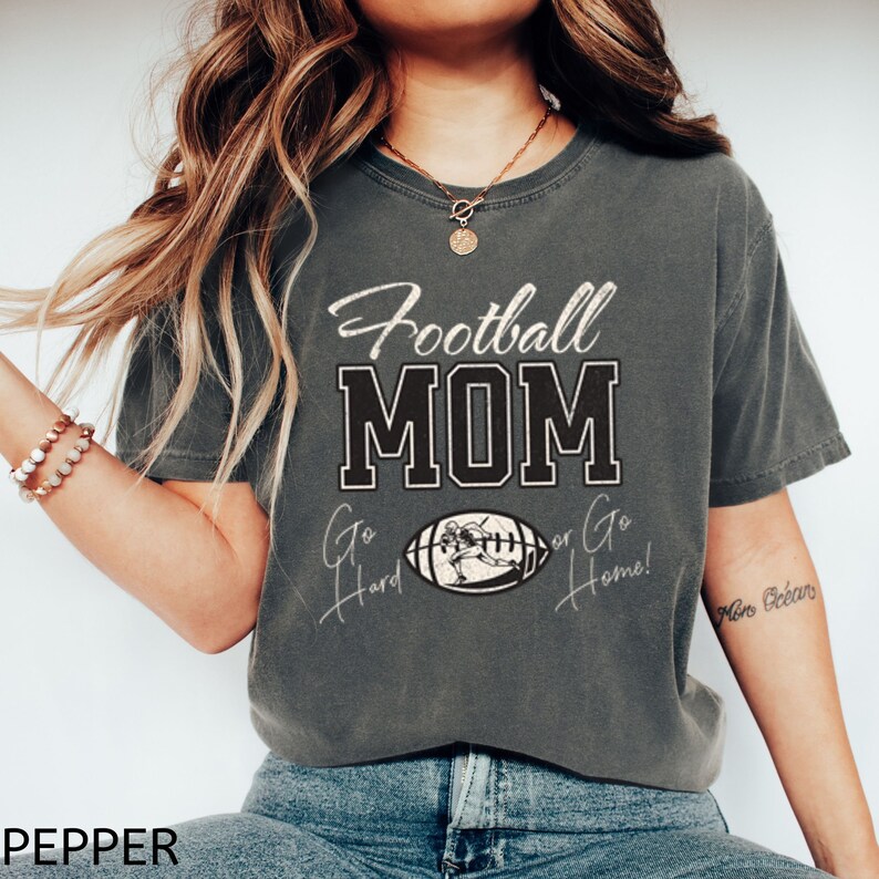 May include: A gray t-shirt with the text "Football MOM Go Hard or Go Home!" in black and white. The shirt features a graphic of a football player running with the ball.