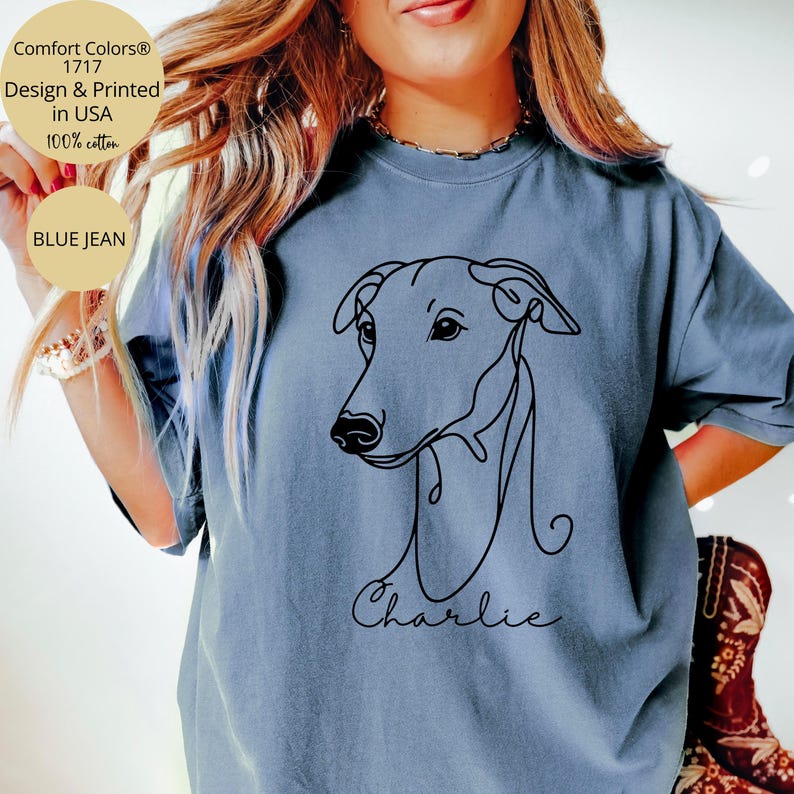 May include: Blue jean Comfort Colors t-shirt with a black line drawing of a dog's head and the name "Charlie" in script. The shirt is 100% cotton and printed in the USA.