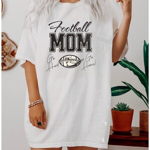 May include: White oversized t-shirt with black text that reads "Football MOM Go Hard or Go Home!" and a black and white illustration of a football player running with the ball.