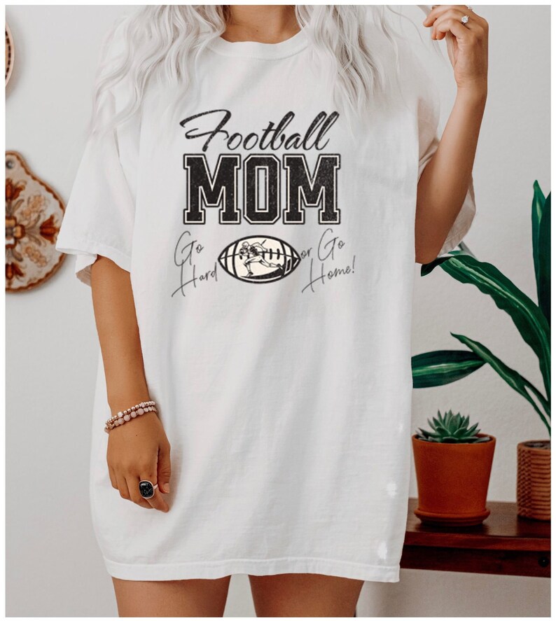 May include: White oversized t-shirt with black text that reads "Football MOM Go Hard or Go Home!" and a black and white illustration of a football player running with the ball.