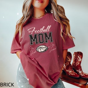 May include: A maroon t-shirt with the text "Football Mom" in black and white. The shirt also has the text "Go Hard or Go Home!" in pink and white with a football graphic.