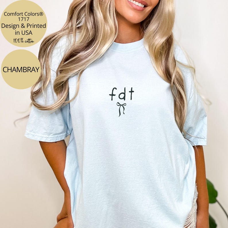Peut inclure: T-shirt bleu clair avec le texte "fdt" et un motif de n&oelig;ud noir. Le t-shirt est en 100% coton et imprim&eacute; aux &Eacute;tats-Unis. Le t-shirt est un mod&egrave;le Comfort Colors 1717 et de couleur chambray.