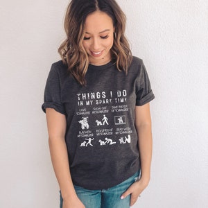 May include: A dark grey heather t-shirt with a white graphic that says "Things I do in my spare time" and lists activities related to owning a schnauzer dog.