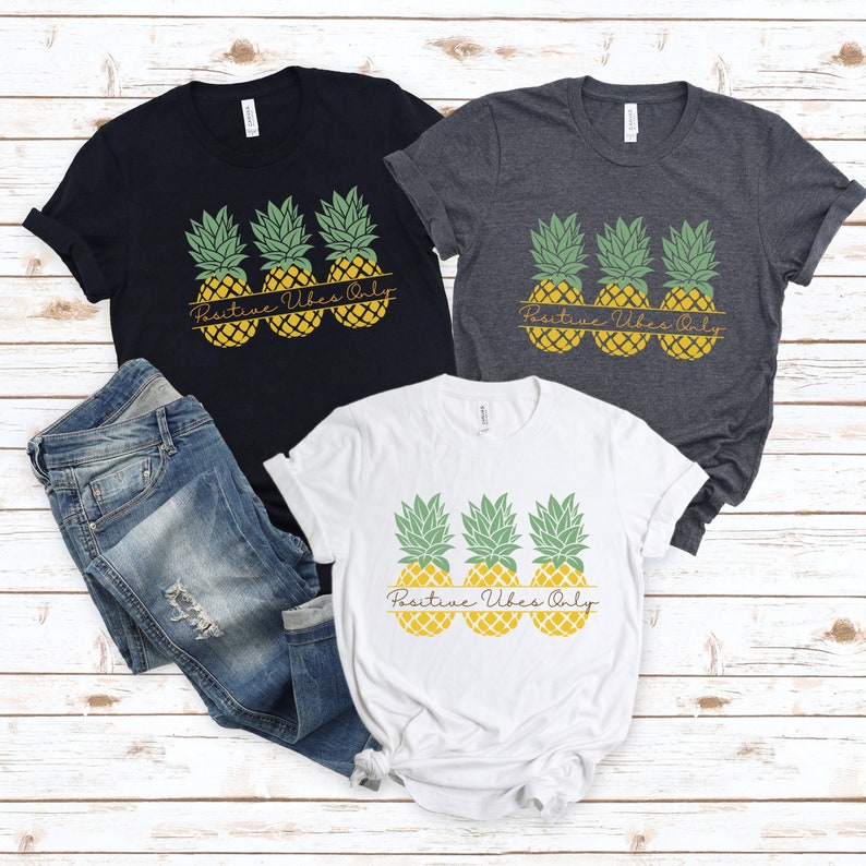 May include: Three white t-shirts with a graphic of three pineapples and the text "Positive Vibes Only".