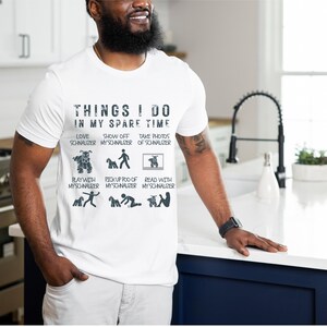 May include: White t-shirt with a black graphic that says "Things I do in my spare time" and lists activities with a miniature schnauzer. The activities include: love my schnauzer, show off my schnauzer, take photos of my schnauzer, play with my schnauzer, pick up poo of my schnauzer, and read with my schnauzer.