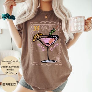 May include: Espresso-colored t-shirt featuring a cocktail design with the words "dirty thirty." The design includes a martini glass with a lemon slice and olives. The shirt also has the text "Comfort Colors 1717 Design & Printed in USA 100% cotton."