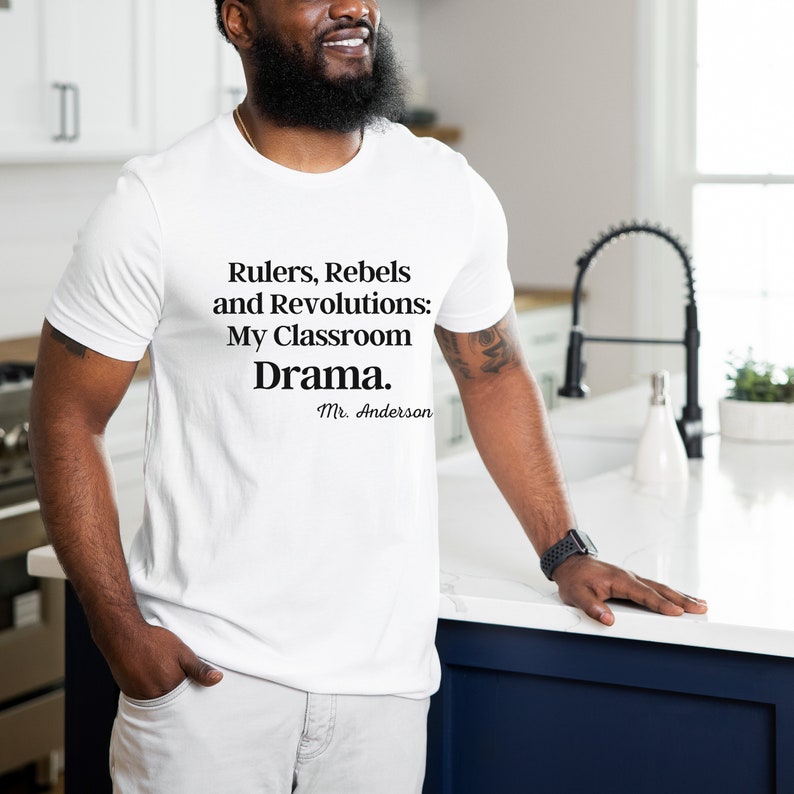 Peut inclure: T-shirt blanc avec du texte noir qui dit "Rulers, Rebels and Revolutions: My Classroom Drama. Mr. Anderson"