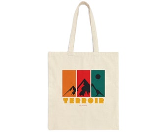 Könnte beinhalten: Eine beige Tragetasche mit einem grafischen Design aus drei Bergen in einem Retro-Farbschema aus Orange, Rot, Grün und Schwarz. Der Text "TERROIR" ist in Gelb unter den Bergen gedruckt.