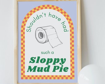 May include: A framed print with a light blue background and a yellow and orange checkered arch. The arch has the text "Shouldn't have had such a Sloppy Mud Pie" inside. A cartoon drawing of a roll of toilet paper is in the center of the arch.