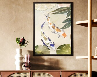 May include: A framed art print featuring two koi fish swimming in a pond with lily pads. The fish have orange, white, and blue markings. The artwork is in a black frame and hangs on a neutral-colored wall.