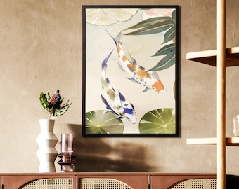 May include: A framed art print featuring two koi fish swimming in a pond with lily pads. The fish have orange, white, and blue markings. The artwork is in a black frame and hangs on a neutral-colored wall.