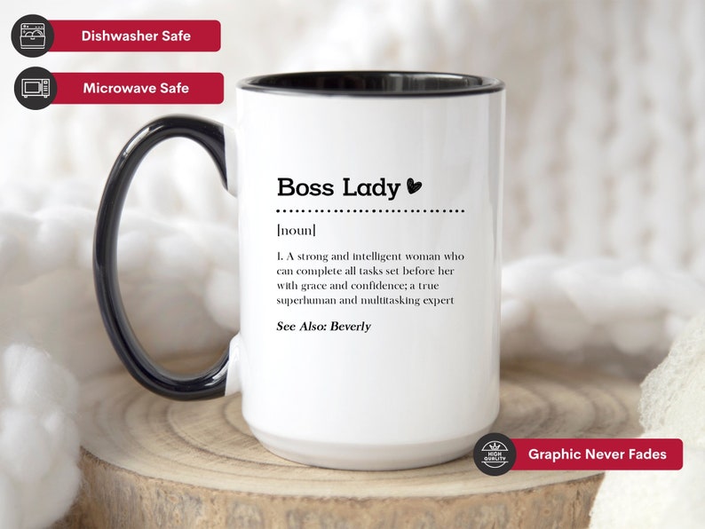 May include: A white ceramic mug with a black handle and interior, featuring the black printed text Boss Lady, noun, and a definition describing a strong and intelligent person who completes tasks with grace and confidence, including the text See Also: Beverly.