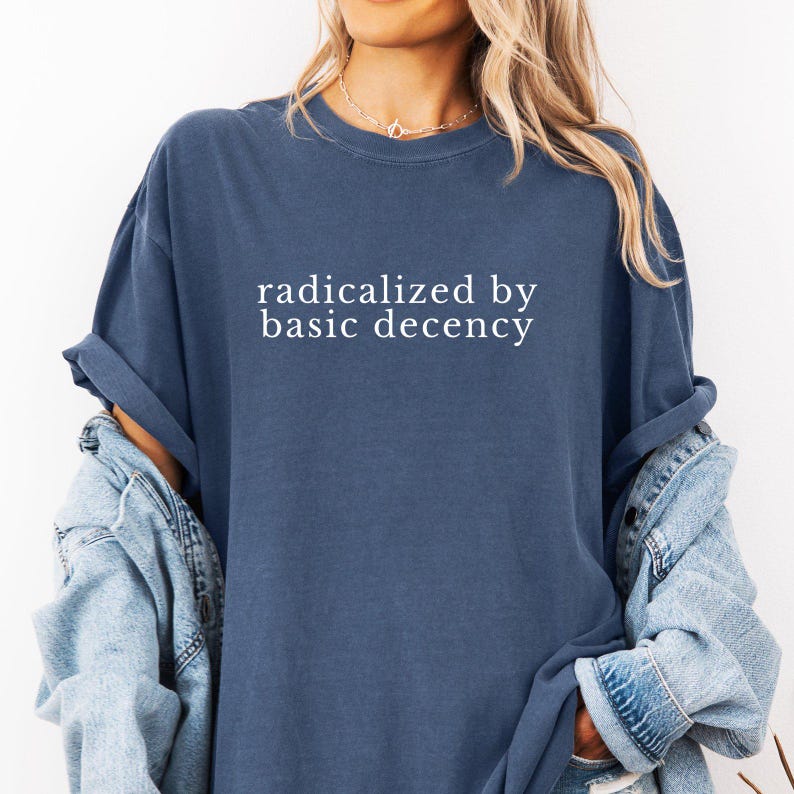 Op de afbeelding: Een oversized navyblauw t-shirt met de tekst "geradicaliseerd door elementaire fatsoen" in wit gedrukt.