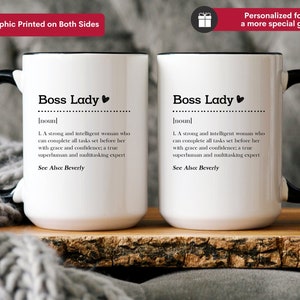 May include: Two white ceramic mugs with black handles and rims. Each mug features black text reading Boss Lady followed by a dictionary-style definition describing a strong, intelligent person who completes tasks with grace, confidence, and multitasking expertise.