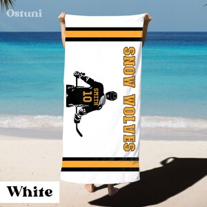 May include: White beach towel with a black silhouette of a hockey player holding a stick. The player is wearing a jersey with the number 10 and the name Smith. The text "SNOW WOLVES" is printed vertically on the right side of the towel. The towel has black and orange stripes.