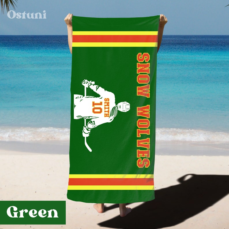 May include: Green beach towel with a hockey player graphic and the text "SNOW WOLVES" in white with orange outlines. The player is wearing a jersey with the number "101" and the name "SMITH" on the back.