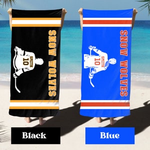 May include: Two beach towels with a hockey player design. The towels are black and blue with white and orange stripes. The player is wearing a jersey with the number 10 and the name Smith. The text "SNOW WOLVES" is written vertically on the towels.