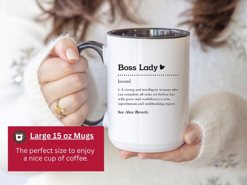 May include: A white ceramic mug with a black interior and handle, featuring the black printed text Boss Lady, a definition of the noun, and the phrase See Also: Beverly. The mug has a capacity of 15 oz as indicated by the text on the image.