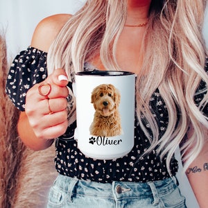 Op de afbeelding: Witte keramische mok met een zwarte rand en handvat. De mok heeft een gekleurde illustratie van een golden doodle hond met de naam "Oliver" gedrukt onder de hond.