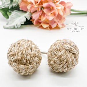 May include: Two brown and white rope cabinet knobs with a knotted design.