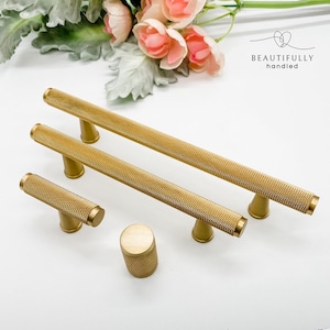 May include: Set of five gold-toned cabinet hardware pulls. The set includes three long pulls, one short pull, and one knob. All pieces have a textured, diamond-shaped pattern.