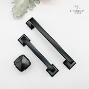 May include: Two black square-shaped cabinet pulls with a flat, rectangular design and a black square knob.