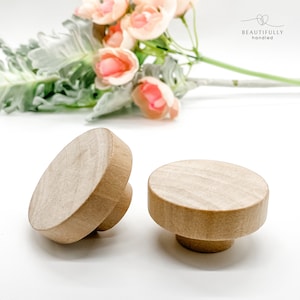 May include: Two wooden knobs with a natural finish. The knobs are round and have a slightly raised edge. They are perfect for adding a touch of rustic charm to any home decor project.