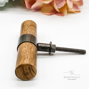 May include: A wooden cabinet knob with a metal band and a screw. The knob is brown and the metal band is silver.