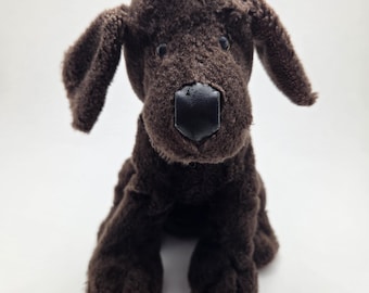 Op de afbeelding: Een bruin pluchen hondenspeelgoed met een zwarte neus en slappe oren. Het knuffel is rechtopstaand, met zijn poten zichtbaar. Het speelgoed heeft een getextureerd uiterlijk en is ontworpen om op een Labrador Retriever te lijken.