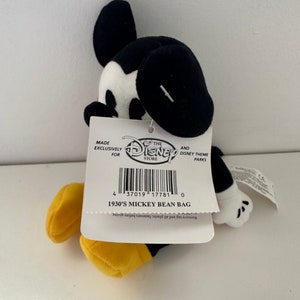 May include: Black and white Mickey Mouse bean bag plush toy with yellow shoes. The tag reads "Made Exclusively for The Disney Store and Disney Theme Parks" and "1930's Mickey Bean Bag".