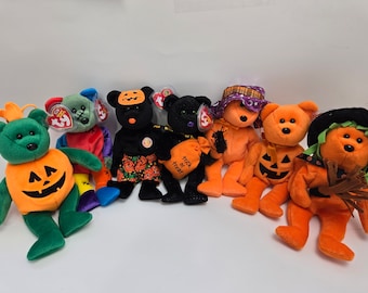 May include: A collection of Halloween-themed plush bears in various colors, including green, orange, and black. Some bears are dressed as pumpkins, while others wear witch hats or carry treat bags. Each bear has a unique design.
