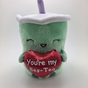 May include: Green plush boba tea cup holding a red heart that says "You're my Bes-Tea".