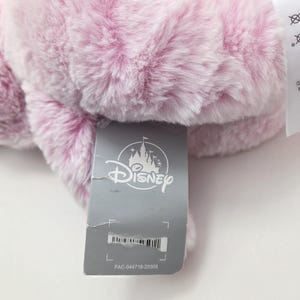 May include: A pink plush Disney character with a gray tag that reads "Disney" and "FAC-044718-20309".