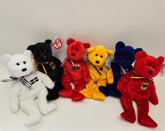 Peut inclure: Six ours en peluche de différentes couleurs, chacun portant le drapeau d'un pays différent. Les ours sont disposés en rangée, l'ours blanc à gauche et l'ours rouge à droite.