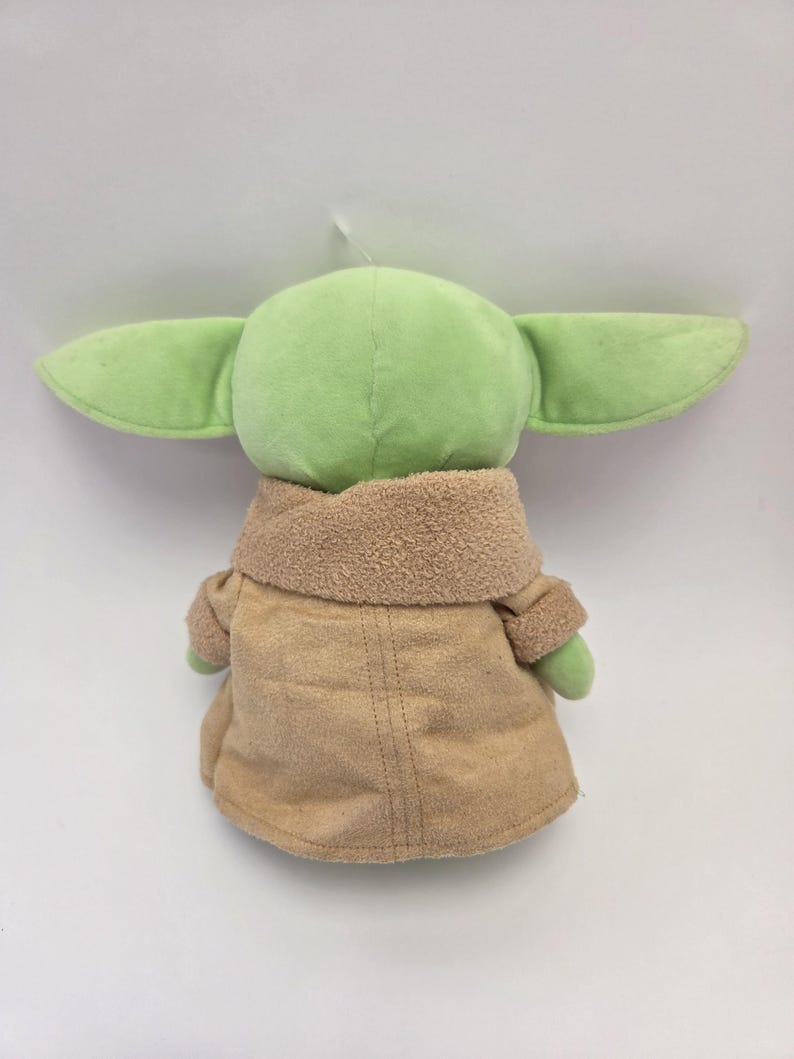 May include: A green plush toy with large ears and a brown coat. The toy is a popular character from the Star Wars franchise.