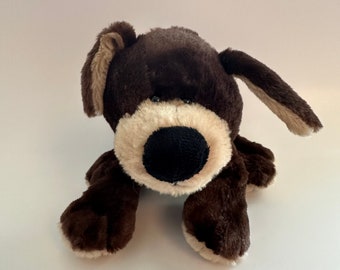 Op de afbeelding: Een bruin en beige pluche hondenspeelgoed met zwarte ogen en een zwarte neus. De hond ligt op zijn buik met zijn poten uitgestrekt.