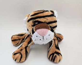 Op de afbeelding: Een pluche tijger speelgoed met bruine en zwarte strepen, een roze neus en witte snorharen. Het speelgoed ligt op zijn buik met zijn poten uitgestrekt.