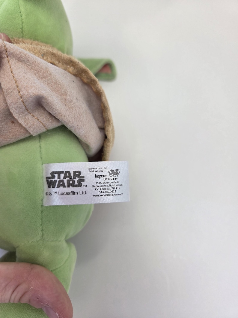 May include: Green plush toy of a Star Wars character with a brown hooded robe. The tag reads "STAR WARS" and "&copy; & &trade; Lucasfilm Ltd."