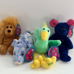 May include: Four plush beanie baby toys, a lion, a pig, a bird, and a mouse. The lion is brown, the pig is blue and white, the bird is green, and the mouse is blue. Each toy has a tag with the year 2000 and the words "Ty" and "Beanie Babies".