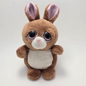 May include: A brown plush bunny with large, round eyes and pink glitter-lined ears. The stuffed animal has a white belly and a small pink nose. It is a cute and cuddly toy.