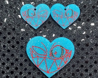 Puede incluir: Tres dijes de corazón azul con brillantina, contorno rojo y diseño de ojo y dientes de dibujos animados en blanco y negro.